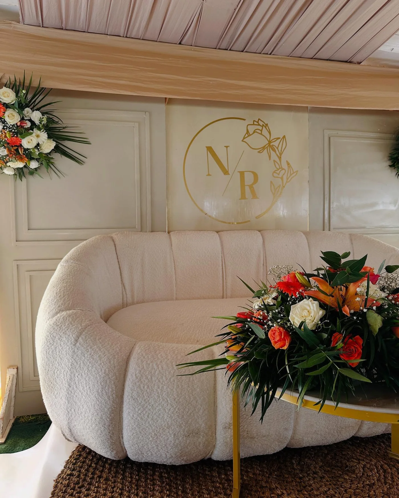 Cream lounge styling with monogrammed backdrop and floral arrangement